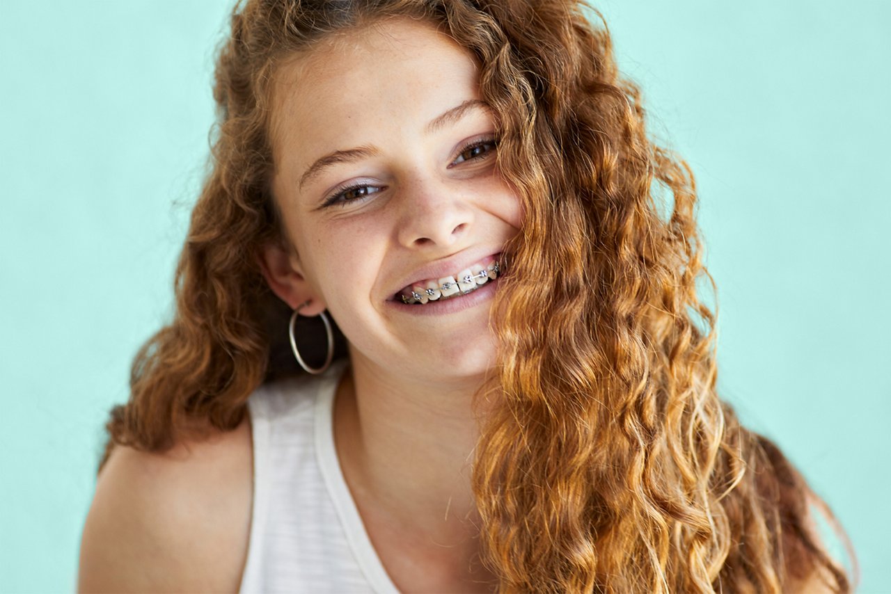 An image of a girl with braces smiling at the camera