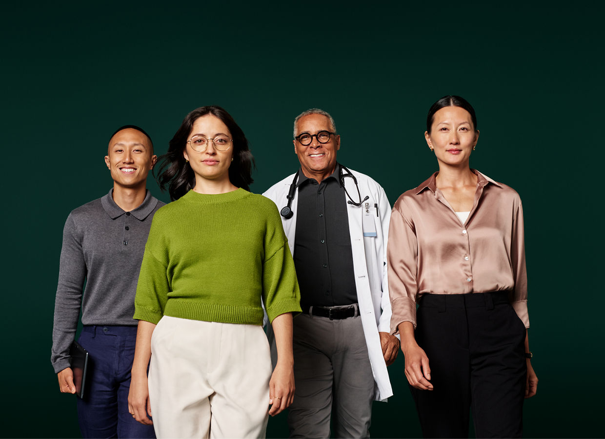 Group portrait of four health information systems professionals walking in a group toward camera on a dark green background.
