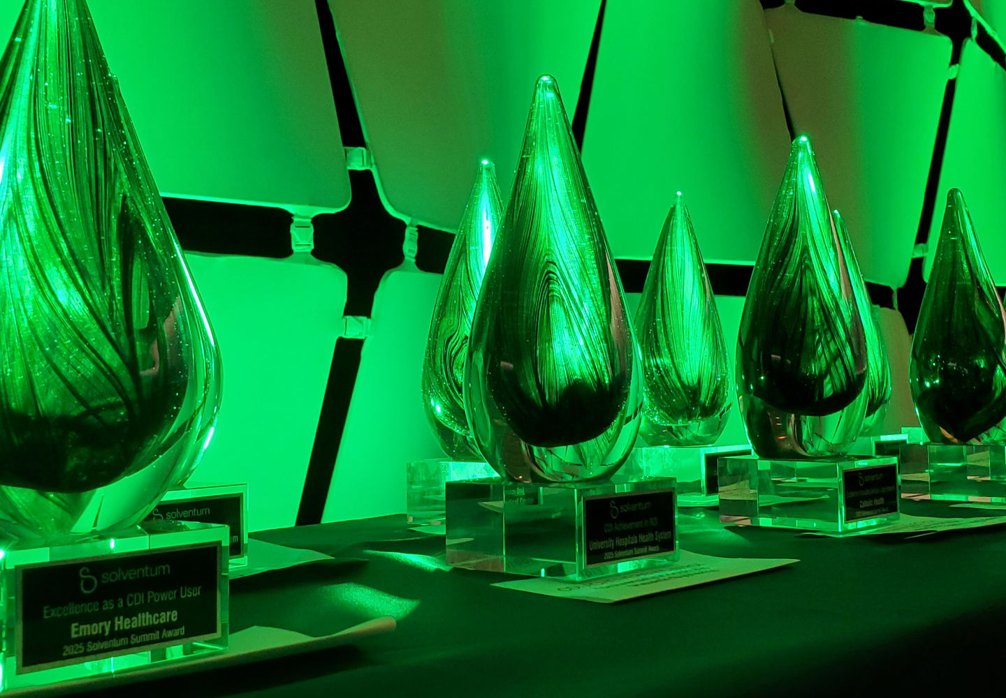 2025 Client Experience Summit (CES) Summit awards trophies lined up with green lighting