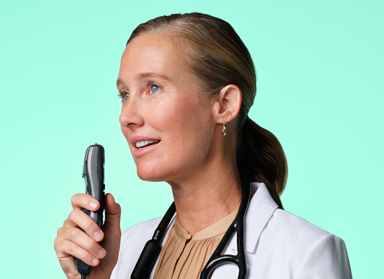 A medical doctor with a stethoscope around their neck speaking into a microphone.