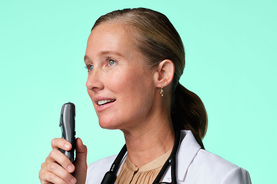 A medical doctor with a stethoscope around their neck speaking into a microphone.