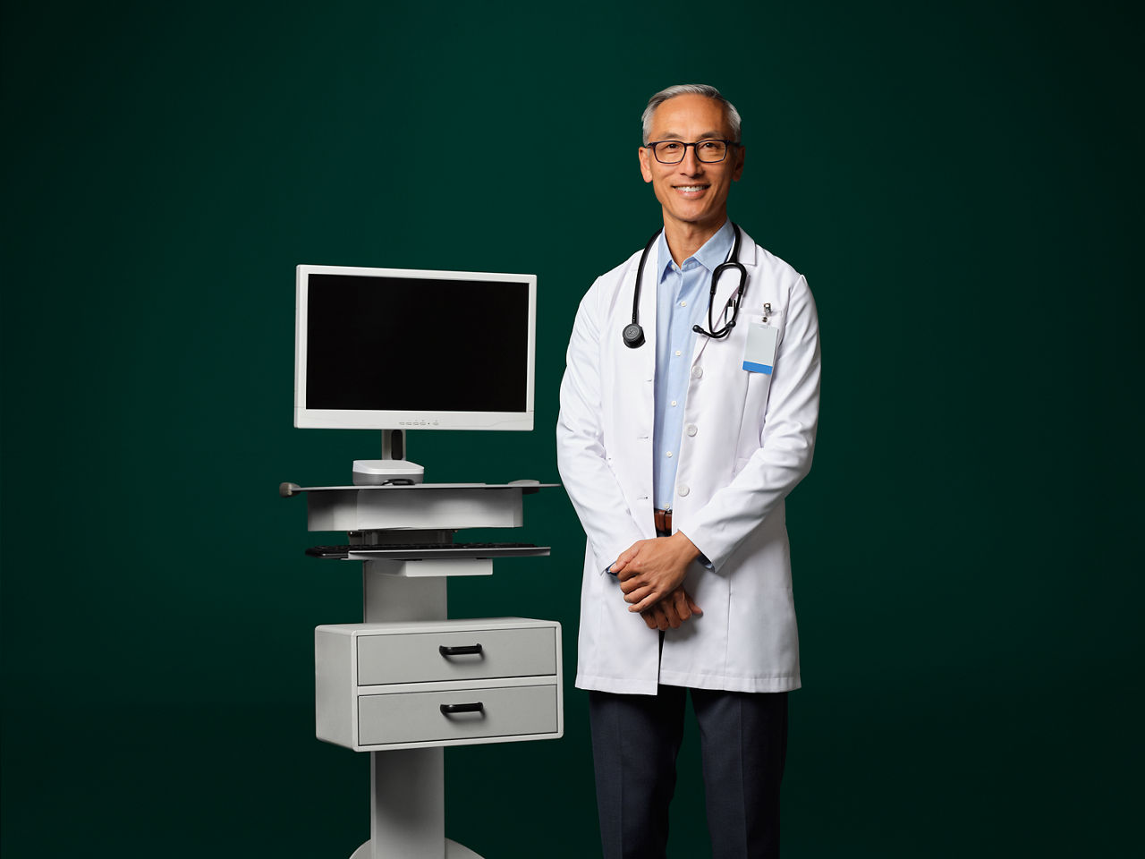 Un médico con un estetoscopio alrededor del cuello parado junto a un dispositivo ambiental.