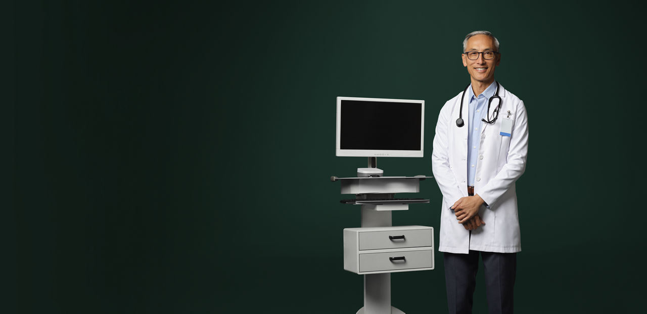 A doctor with a stethoscope around his neck standing next to an ambient listening device.