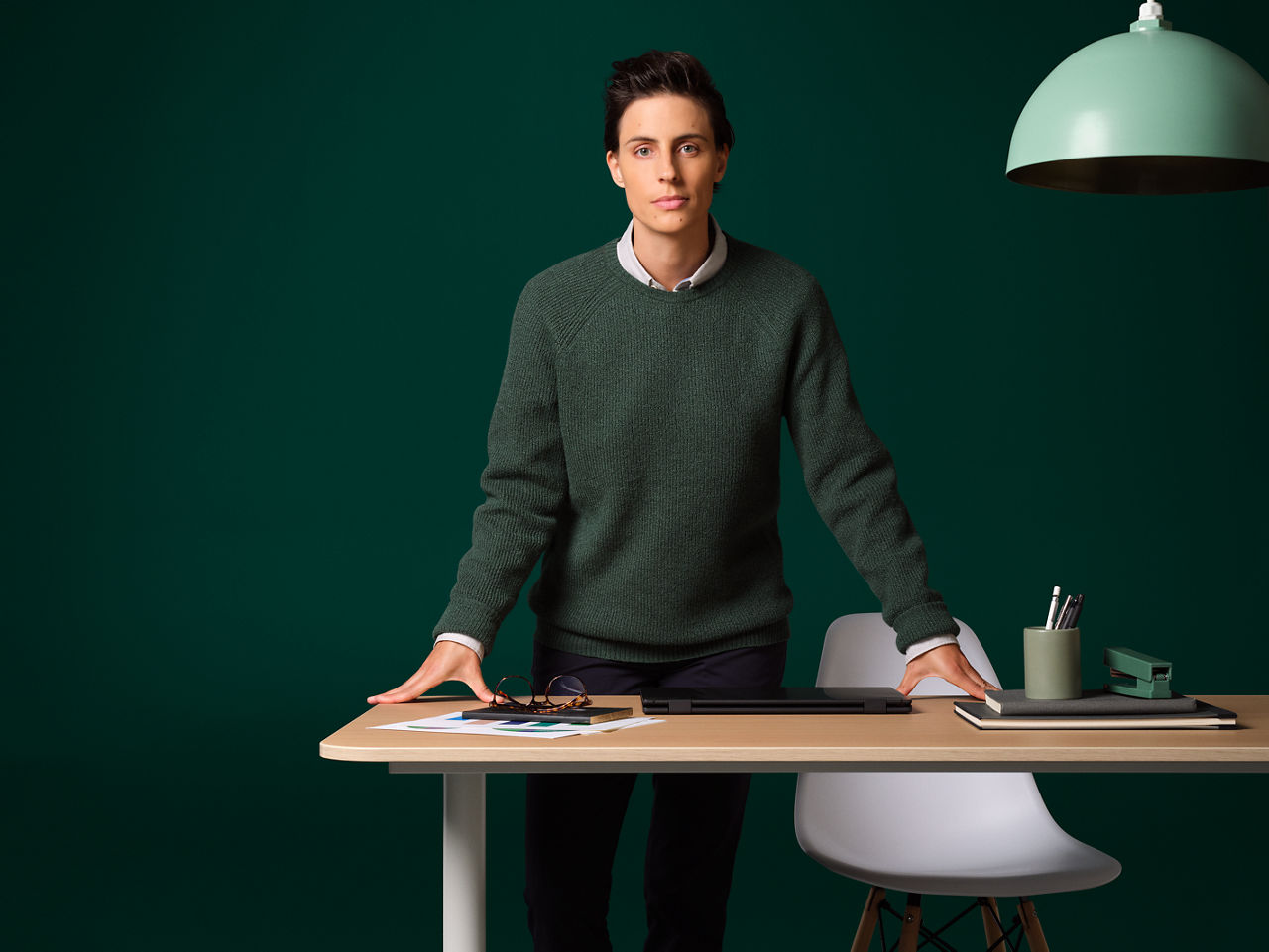 A man stands at a modern desk with a laptop.