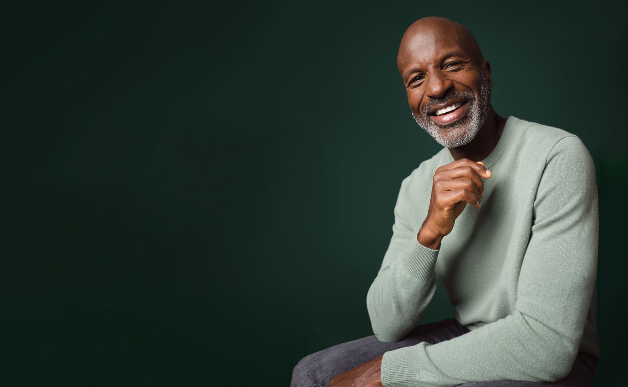 A smiling male who is seated.