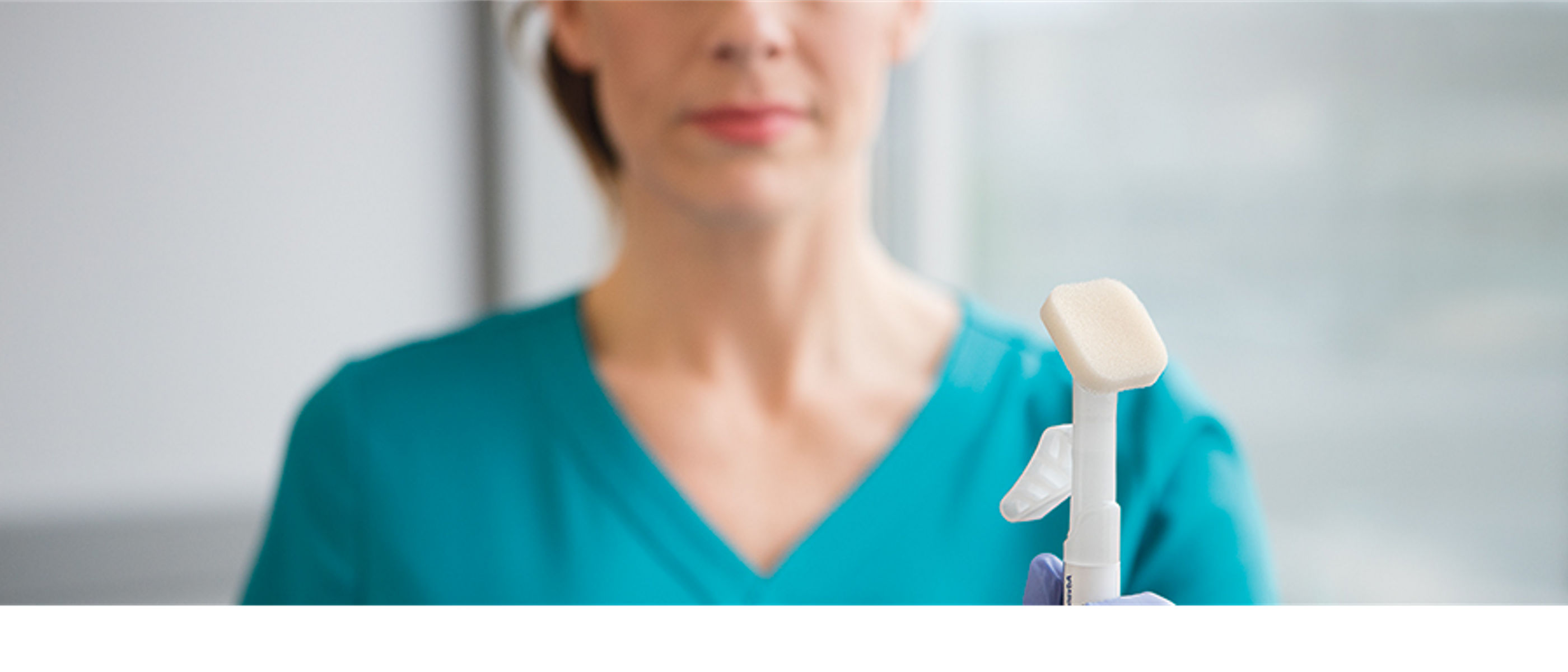 Stylizowane zdjęcie z aplikatorem Cavilon Advanced w centrum uwagi oraz pielęgniarką trzymającą aplikator w rękawicy, poza głębią ostrości. Cavilon Hero Image, Crop 900x450, rgb, jpg