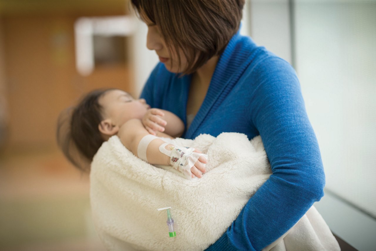 Image of mother holding baby with pediatric dressings and IV