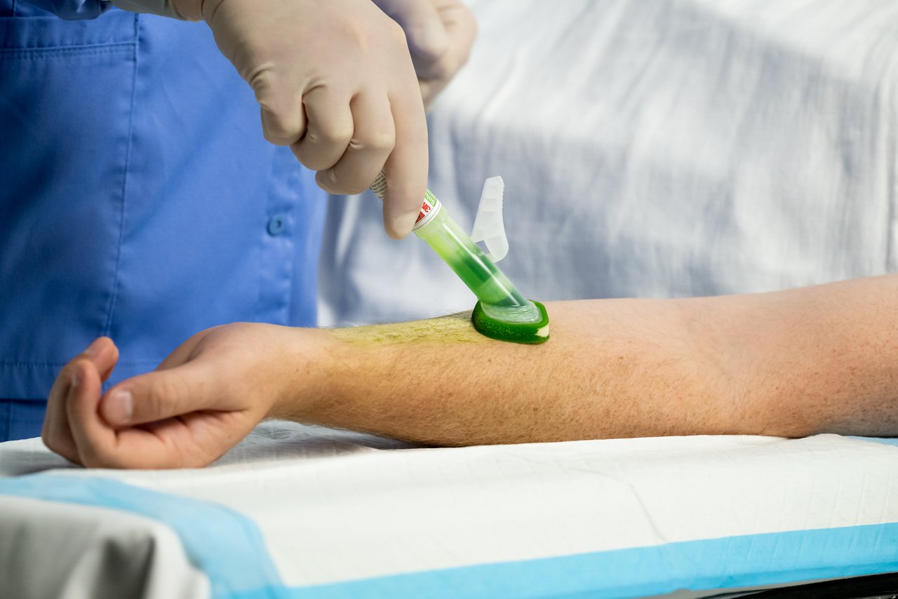 Medisch werker brengt 3M™ SoluPrep™ S Steriele Antiseptische Oplossing aan op de binnenkant van de onderarm van de patiënt, Toepassing op arm, hoge resolutie, 300 dpi, rgb, tiff