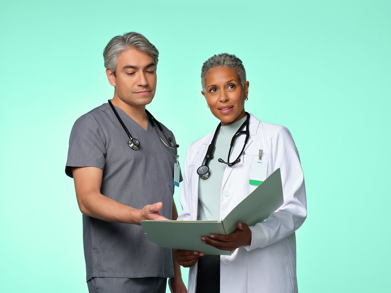 Arzt und Krankenschwester diskutieren über eine Patientenakte.