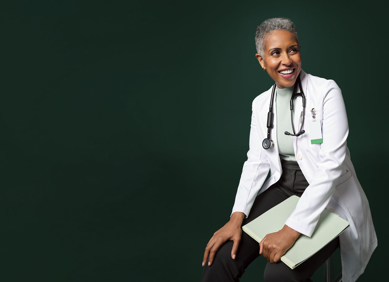 Mulher sorrindo, médica do hospital sentada em um caderno de anotações.