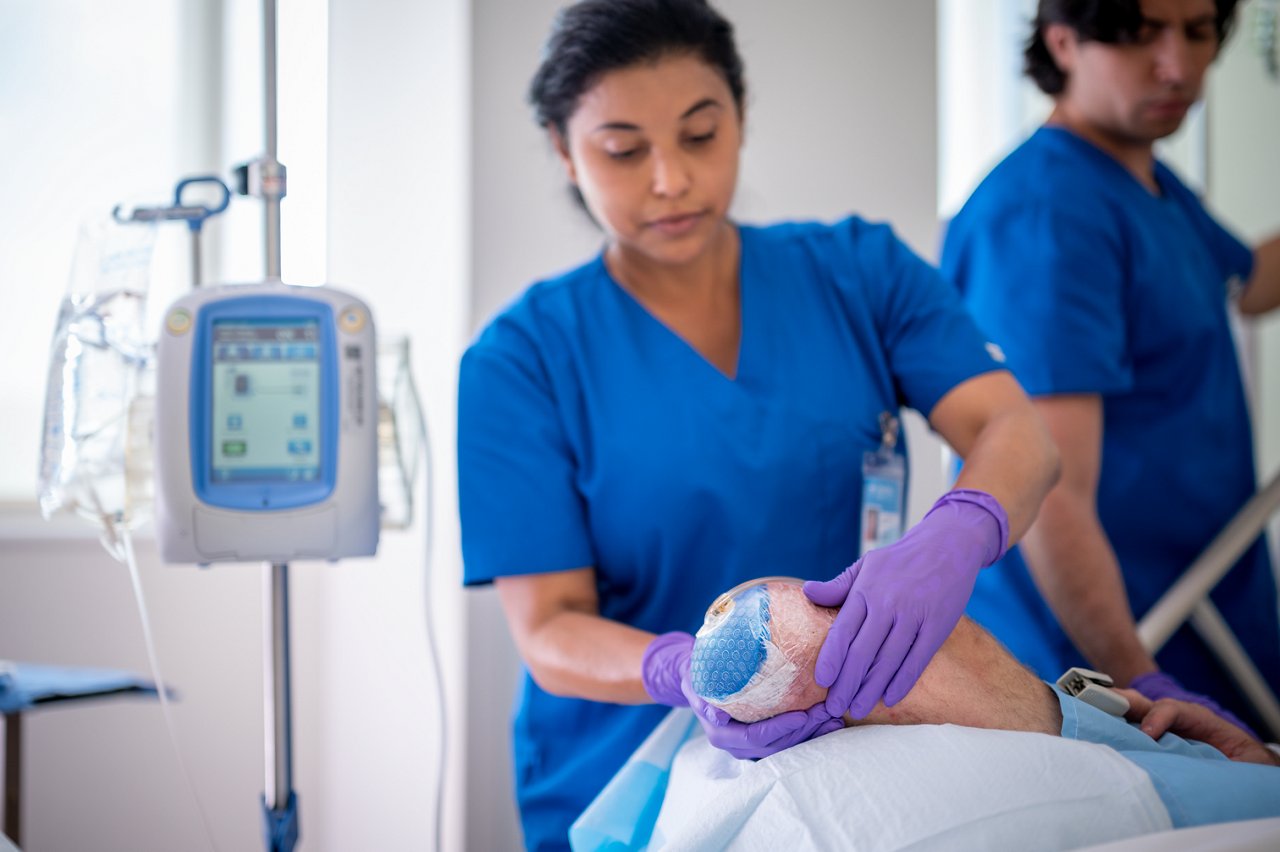 Patient in hospital with nursing staff preparing for and applying VAC therapy for amputation case; photo 2