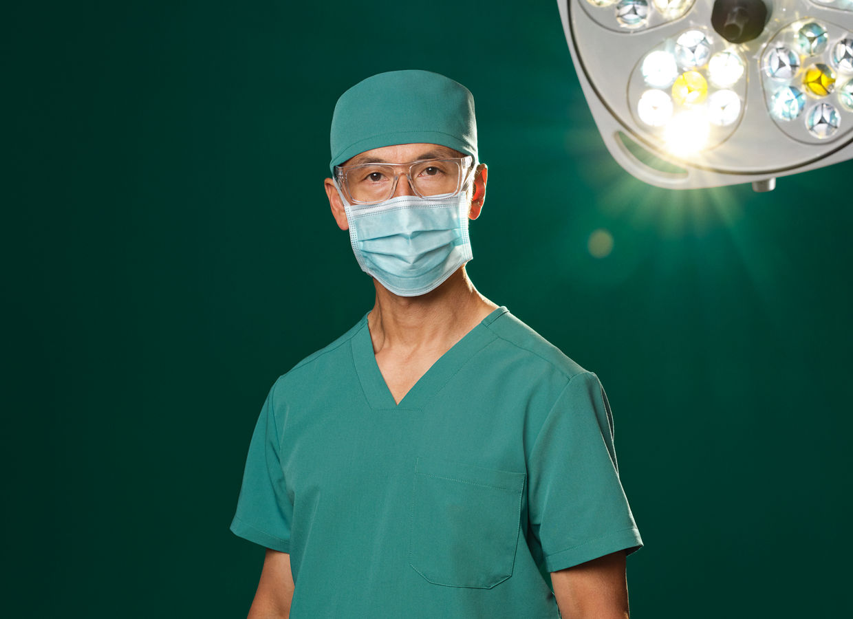 Surgeon in green scrubs with overhead operating room light.