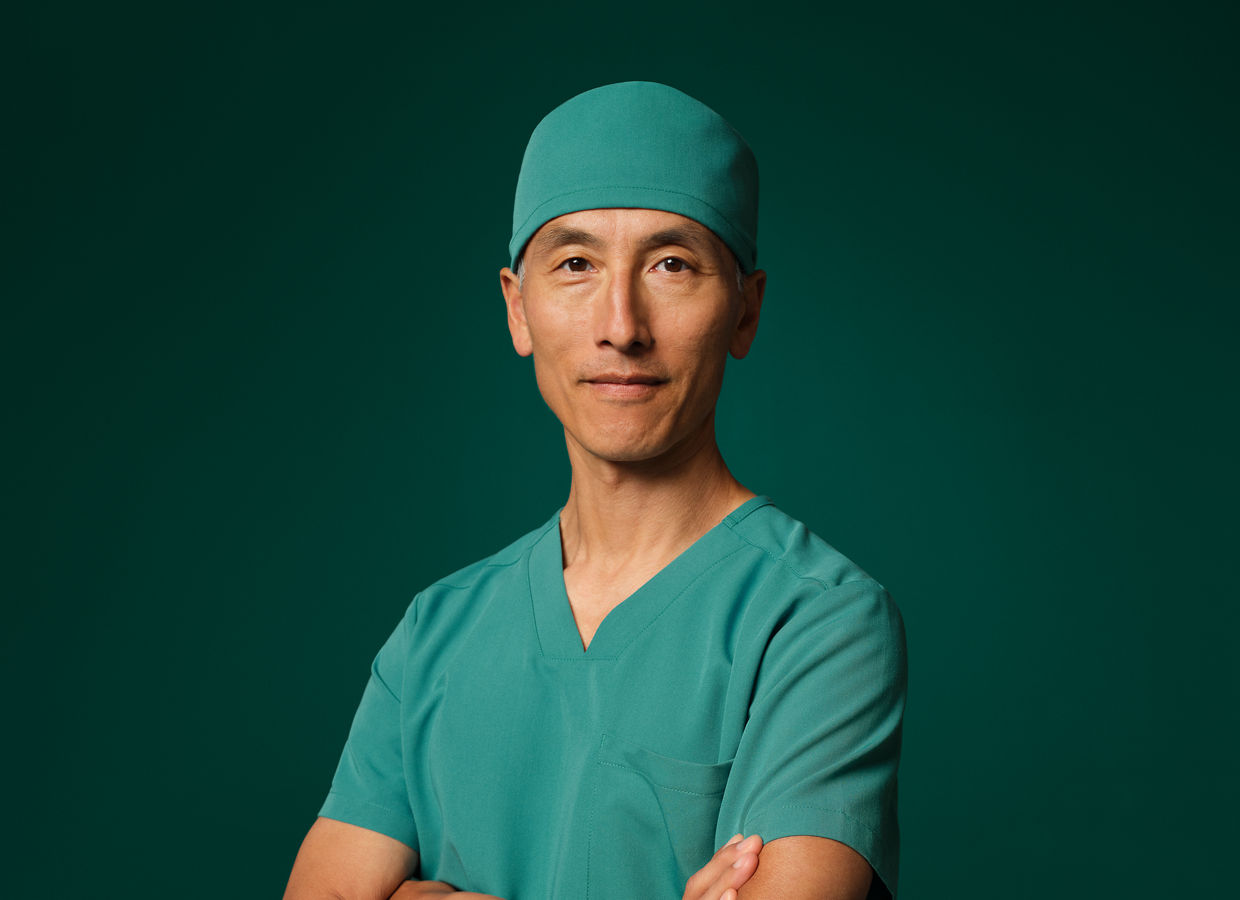 Surgeon in teal scrubs, arms crossed.