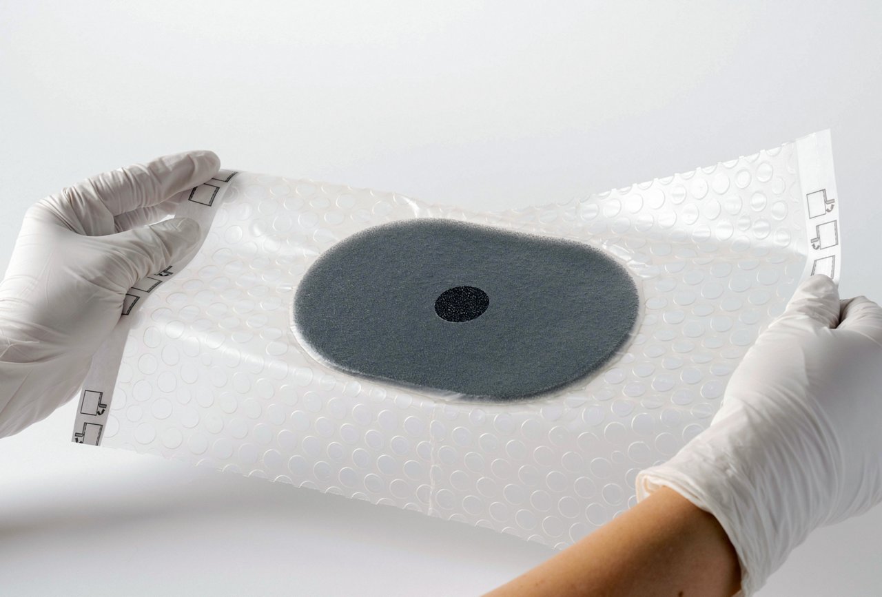 Beauty shot of 3M™ V.A.C.® Peel and Place Dressing with no liner being placed by white gloved hands on a white background. Product Image, rgb, jpg