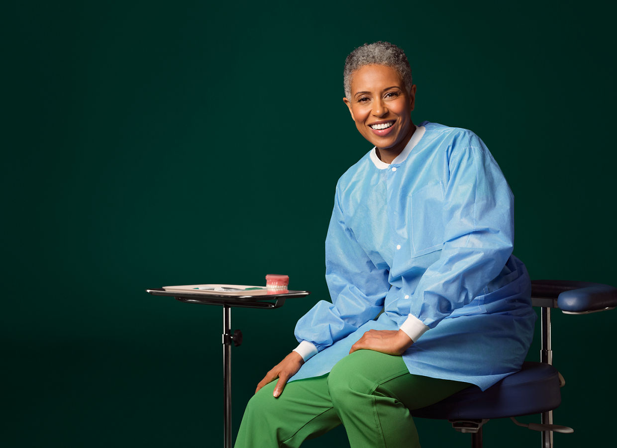 Female dental hygienist seated next to a small table with a typodent on it