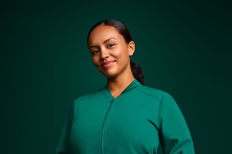 Portrait of a female orthodontist assistant in scrubs and standing on a dark green background.