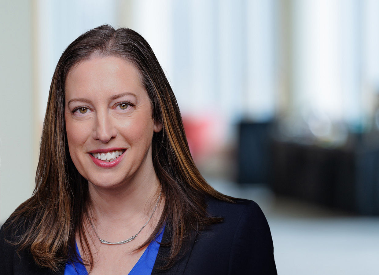 Executive Woman with blue shirt black jacket headshot on an office background