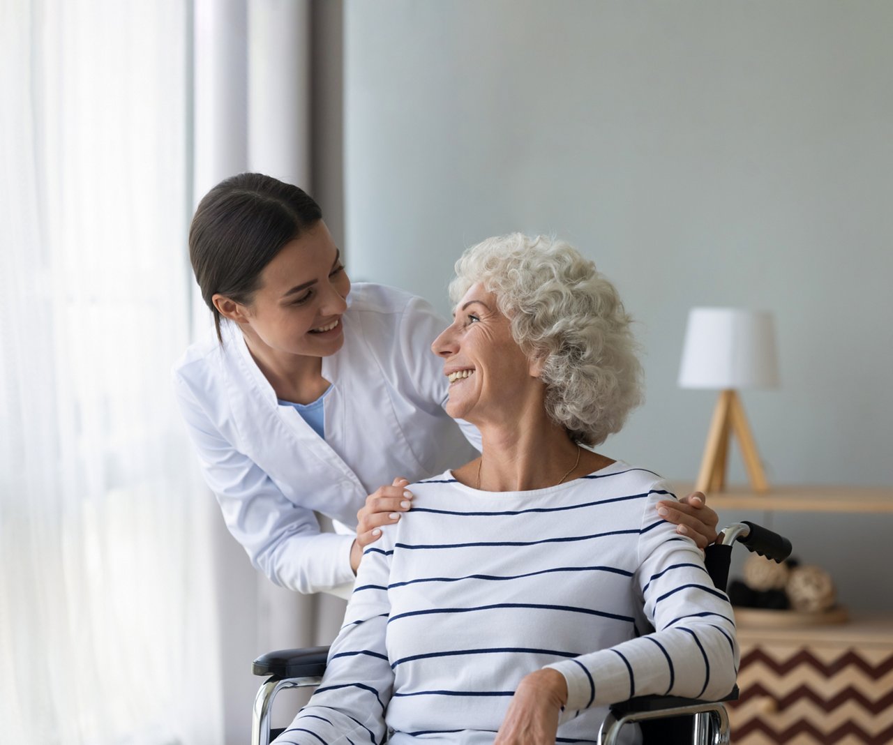 This asset is Shutterstock ID 1681152994. This is licensed from Shutterstock Images. Unlimited seats were licensed there is no charge to use this image. Please download and use as needed, but include this Celum ID in Release Comments for new content loaded to Celum utilizing this asset. Title: Happy female nurse or caregiver talk support positive handicapped old lady patient sitting in wheelchair in hospital, young woman doctor give help take care of mature handicapped grandmother. Retouched for 3M™ V.A.C.® Therapy bridging techniques brochure. 70-2013-1088-8