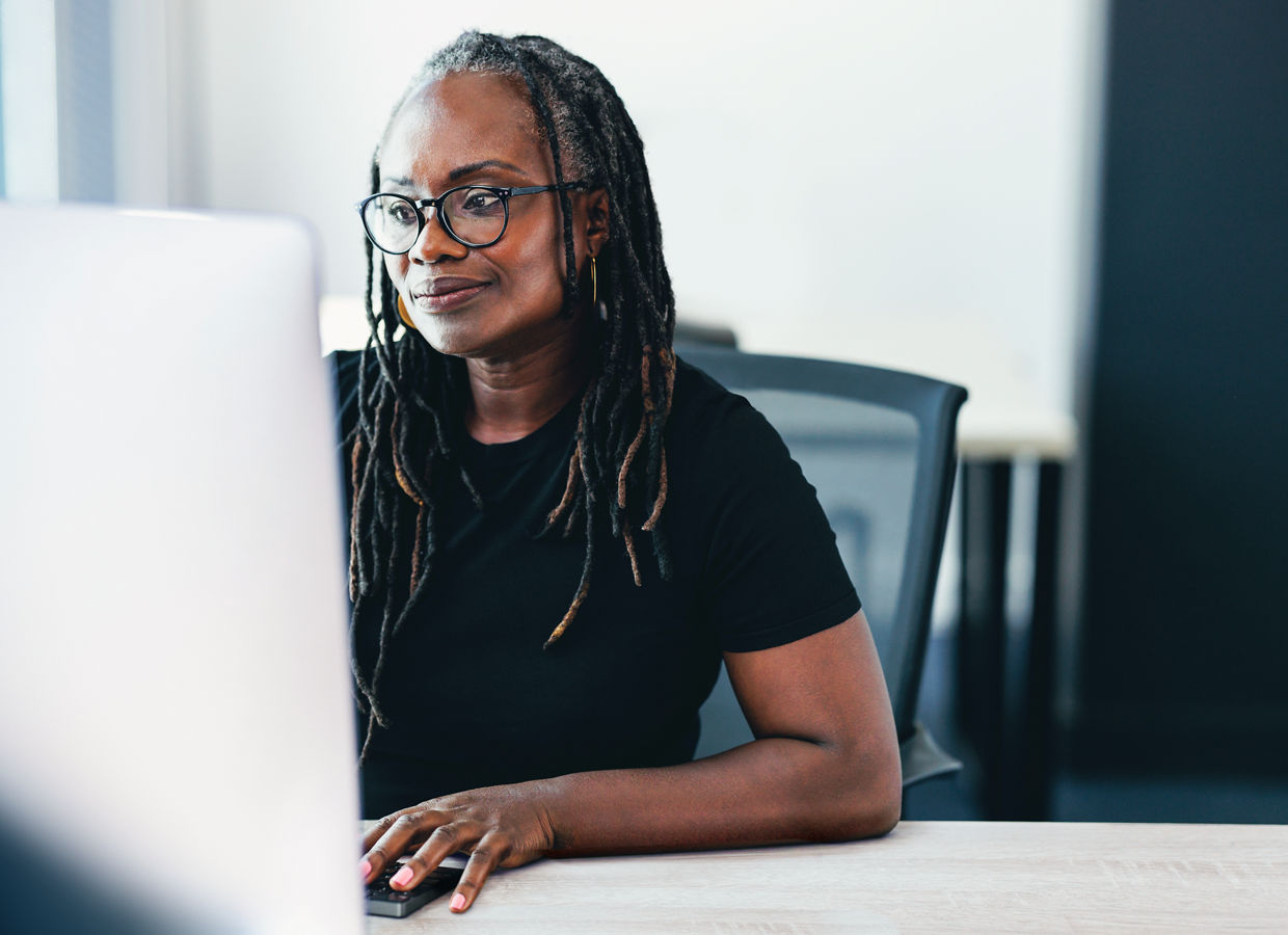 Office worker seated at her desk while working at a computer.