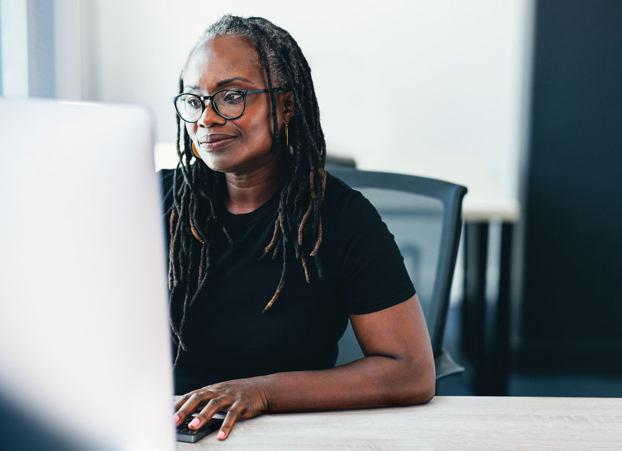 Ältere Geschäftsfrau, die aufmerksam auf ihren Computerbildschirm schaut, während sie an einer Aufgabe arbeitet. Afrikanische Geschäftsfrau, die ihr Fachwissen nutzt, um in einem Büro erfolgreiche Ergebnisse zu erzielen.