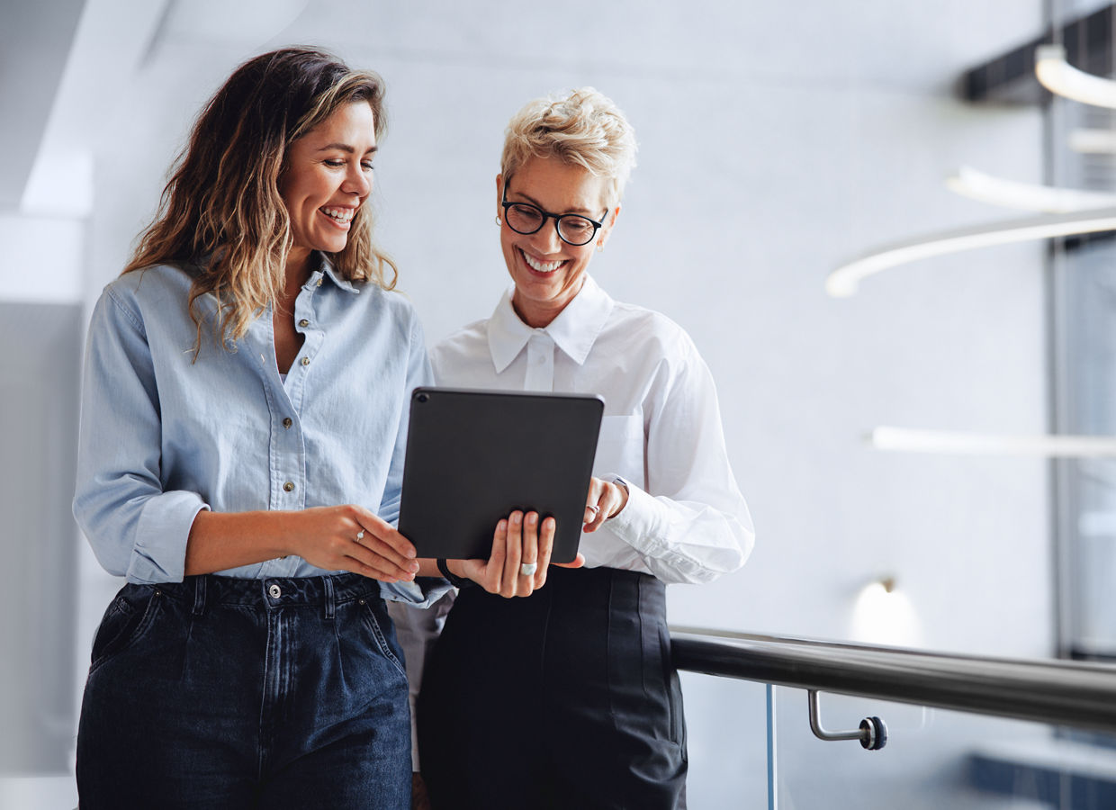 Two office professionals viewing a tablet screen in a lobby.