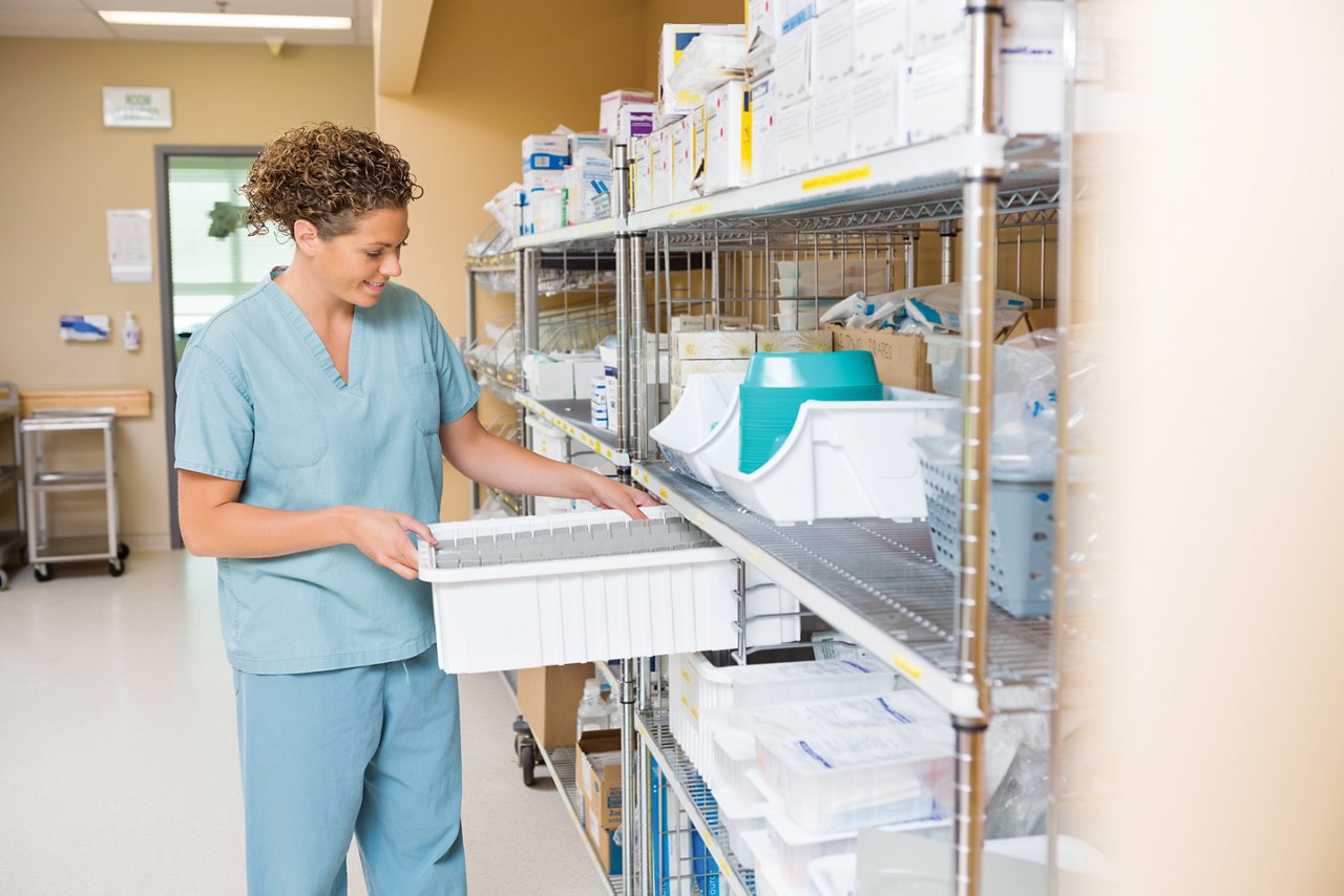 Krankenschwester im mittleren Erwachsenenalter, die einen Behälter auf einem Regal im Lagerraum des Krankenhauses arrangiert; Shutterstock ID 166817597; Bestellung: 970; Auftrag: IPD C3SD Tapes Broschüre; Auftraggeber: Rich.gonzales@schermer.co; Sonstiges: 3M