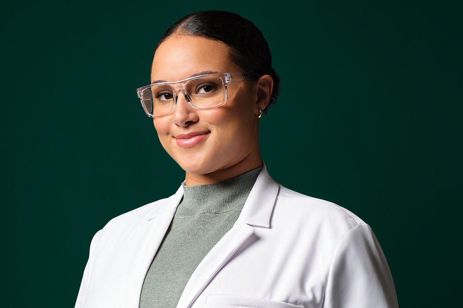 Female application engineer wearing white lab coat, safety googles and blue gloves.