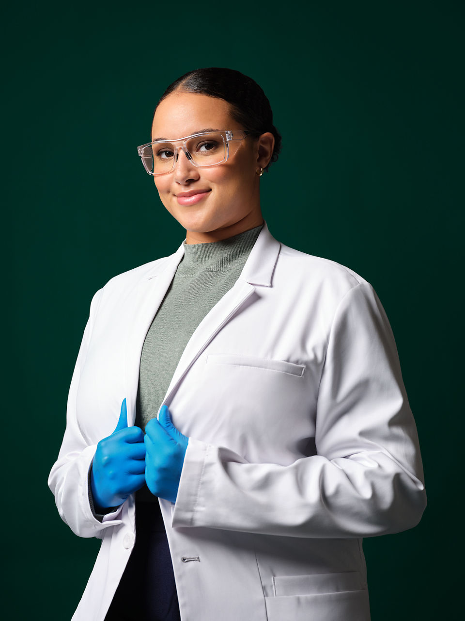 Engenheira de aplicação feminina usando jaleco de laboratório branco, óculos de segurança e luvas azuis