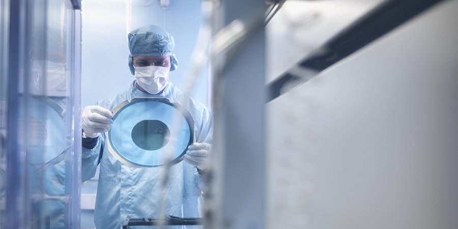 Elektronikarbeiter hält Siliziumwafer an der Schneidemaschine im Reinraum