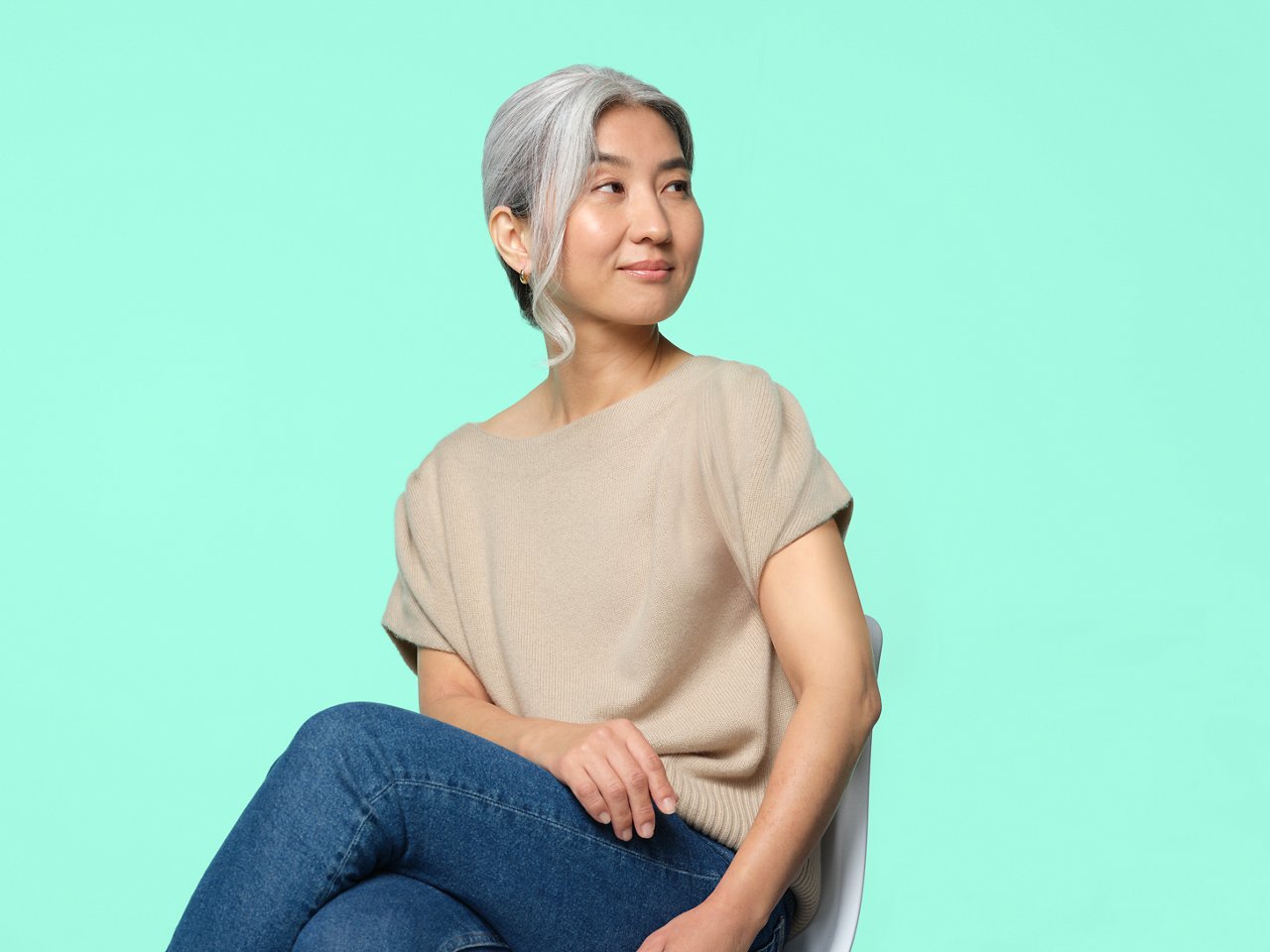 Una mujer con una camisa color beige sentada en una silla.
