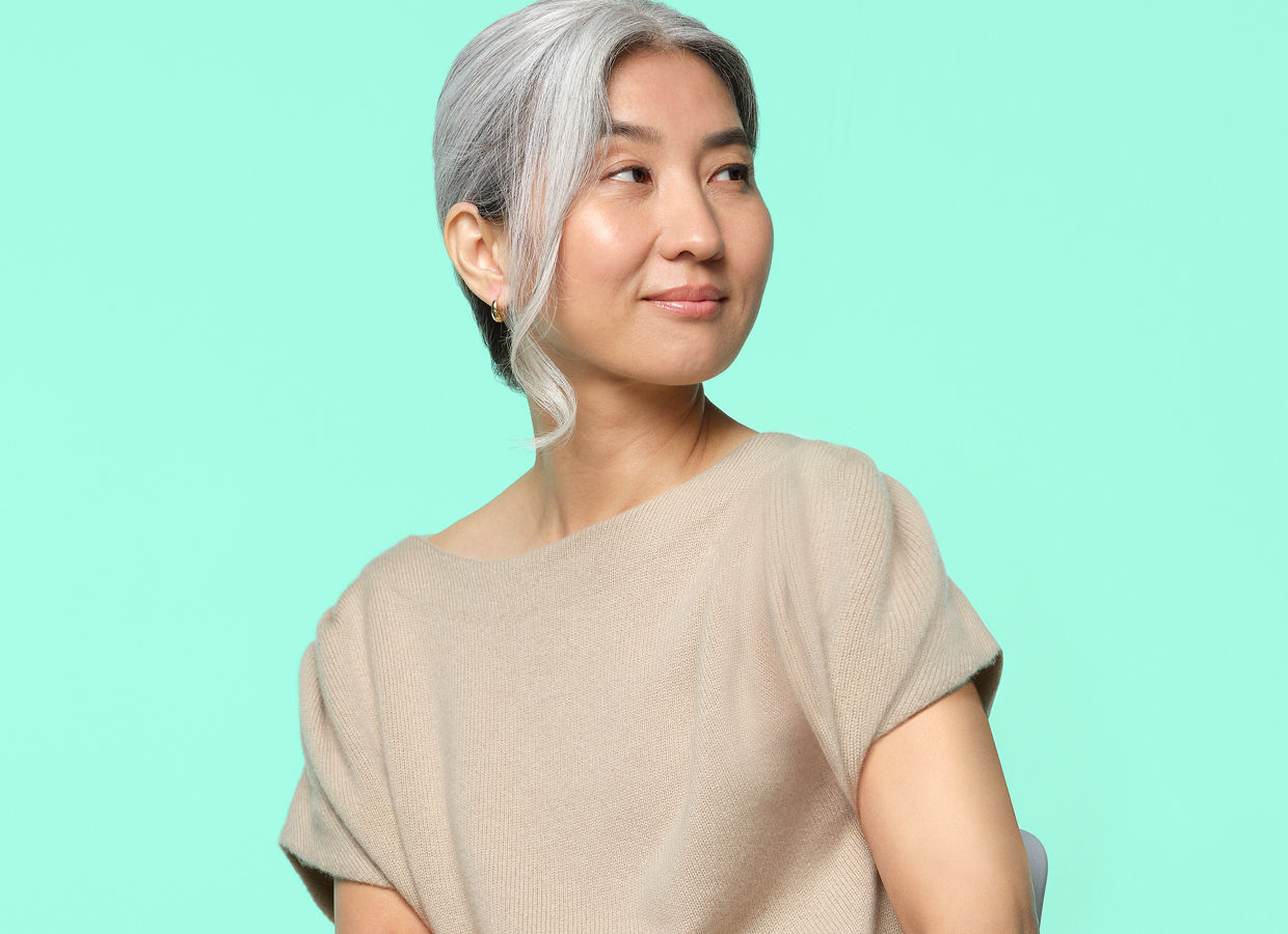 A woman in a tan shirt sitting on a chair.