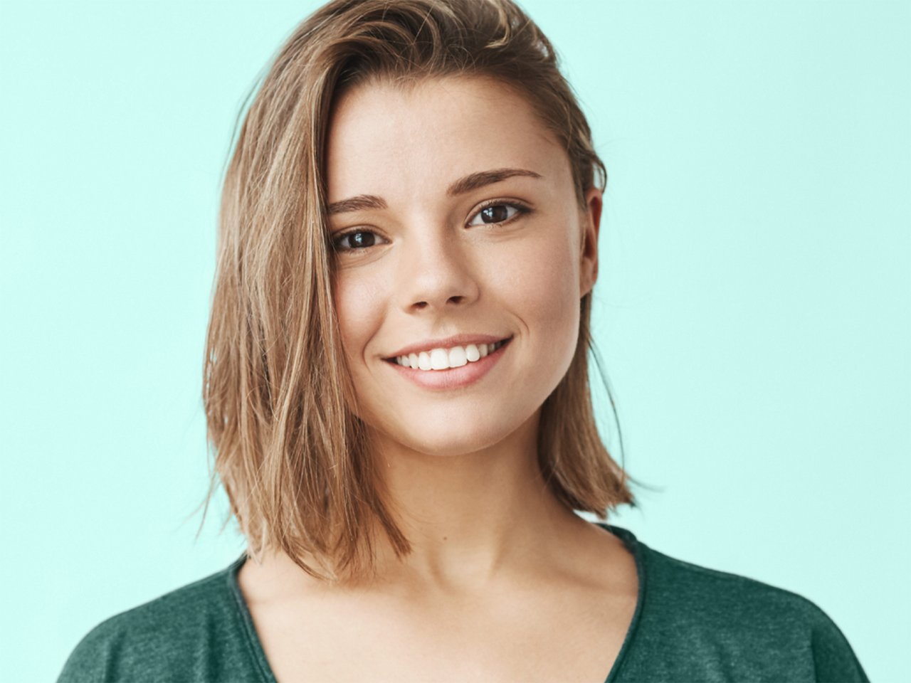 Portrait of woman smiling with teal background