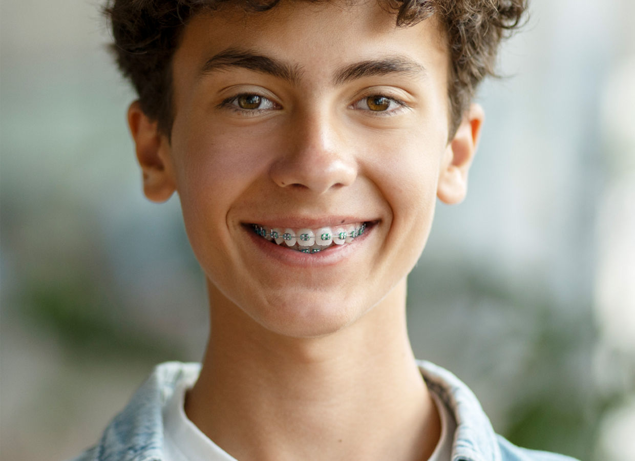 Kuva pojasta, jolla on oikomiskoje, hymyilemässä kameraan