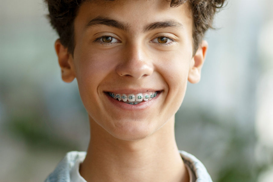 Uma imagem de um menino com suspensórios sorrindo para a câmera