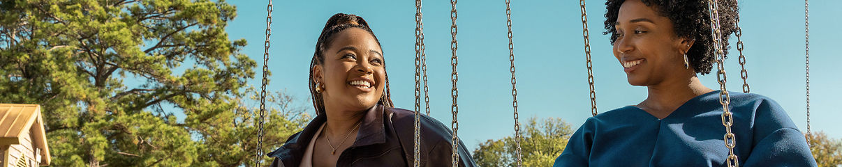 Two women enjoying the swings at a park