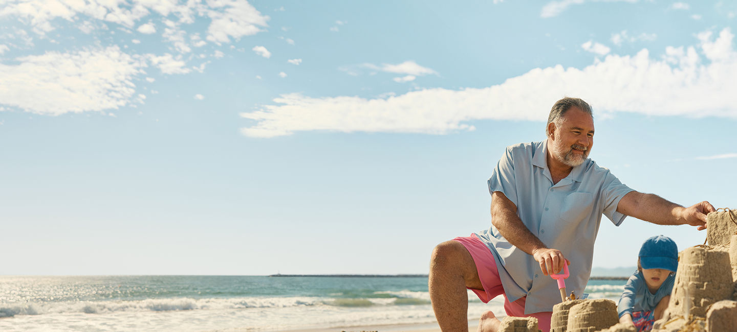 Man on the beach making sand castles with a toddler
