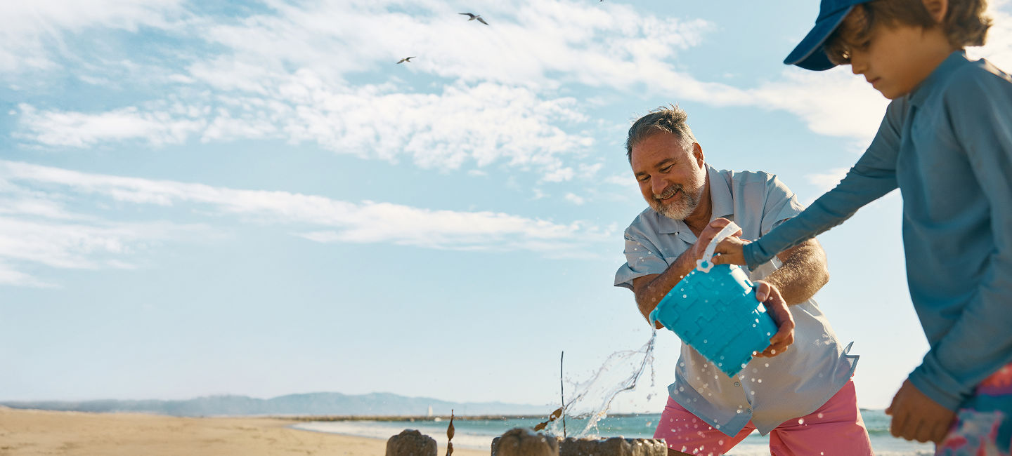Man on the beach making sand castles with a child