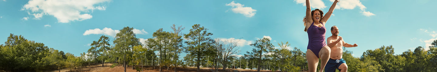 Two people in swimwear jumping into a lake