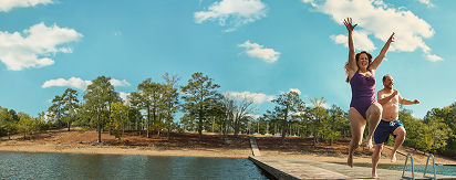 Two people in swimwear jumping into a lake