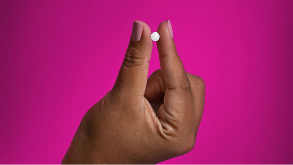 A hand holding a Wegovy pill between the thumb and pointer finger.