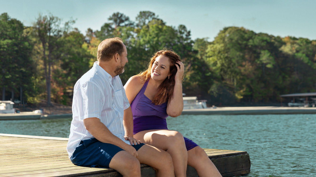 Two people sharing a conversation while sitting at the edge of the lake 