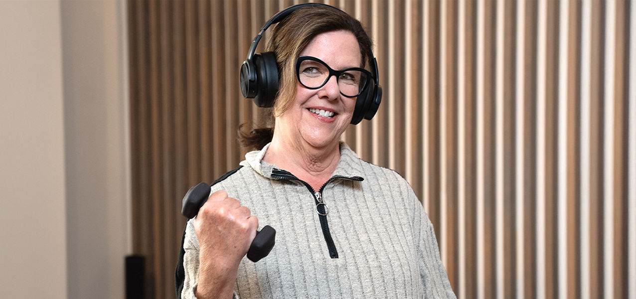 Jane wearing headphones and lifting a dumbbell
