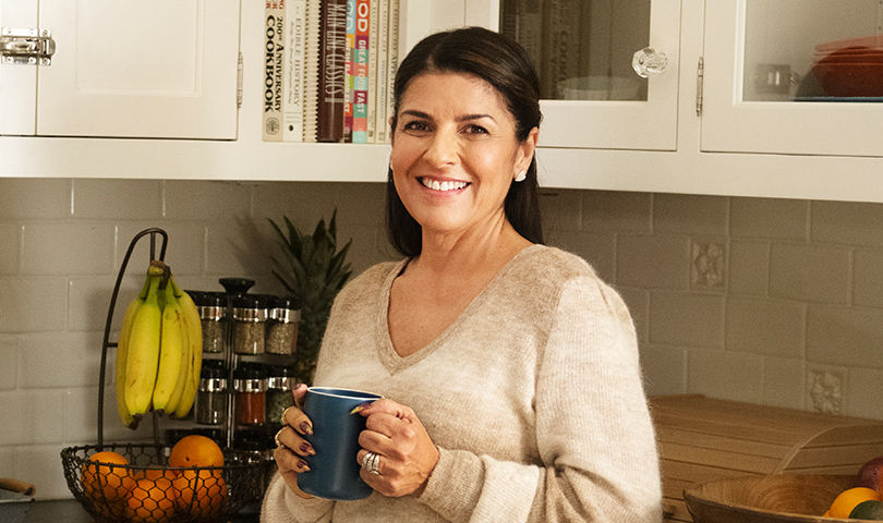 Maria smiling and holding a mug in kitchen