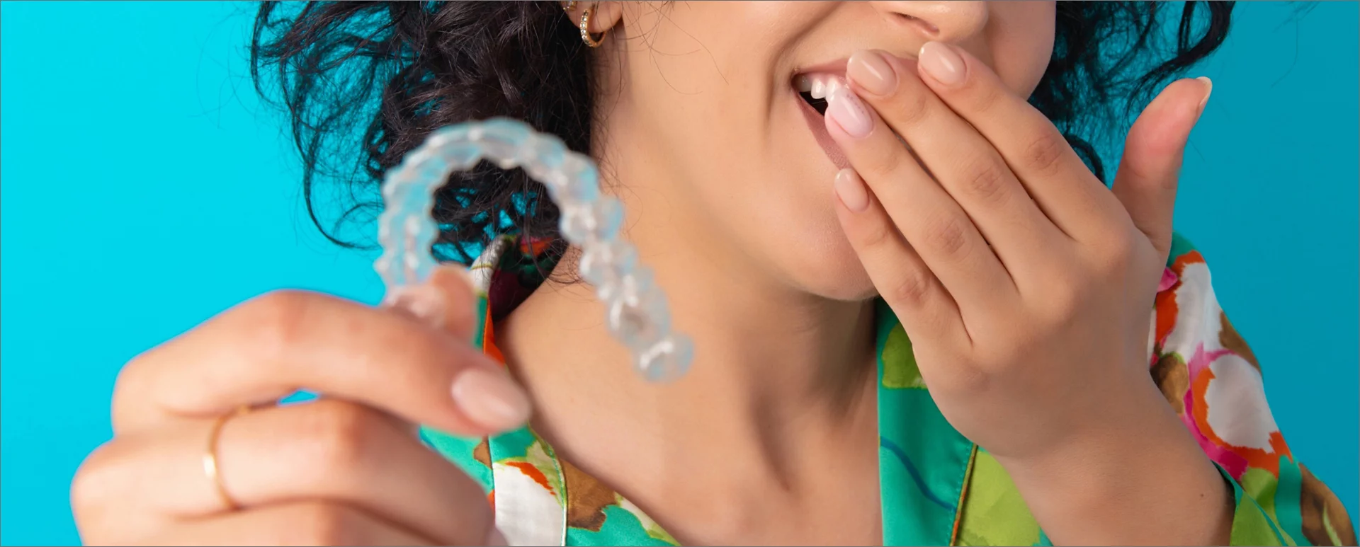 Woman laughing and holding onto clear aligners