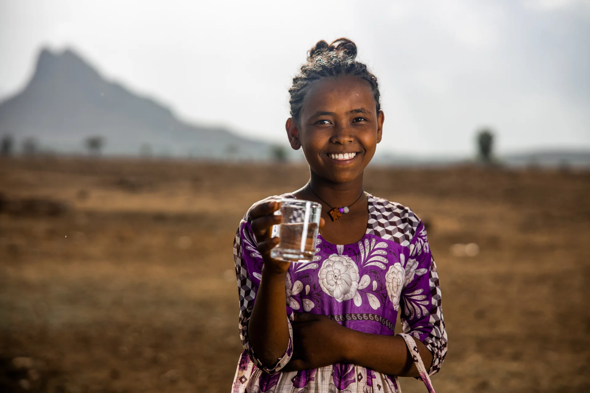 Young girl holding a glass of clean drinking water in Ethiopia