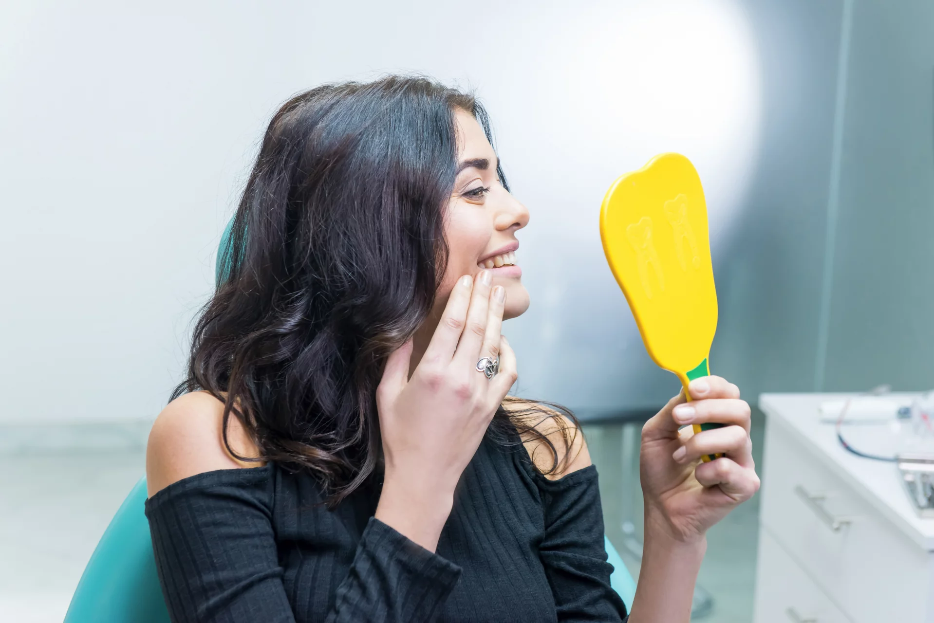 Female checking teeth in mirror. Smiling woman at dentist office. Smile wider and be beautiful.