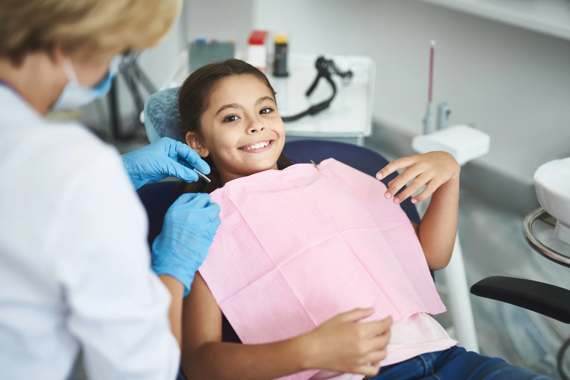 Positive cute girl sitting in the chair of her dentist while expressign happiness