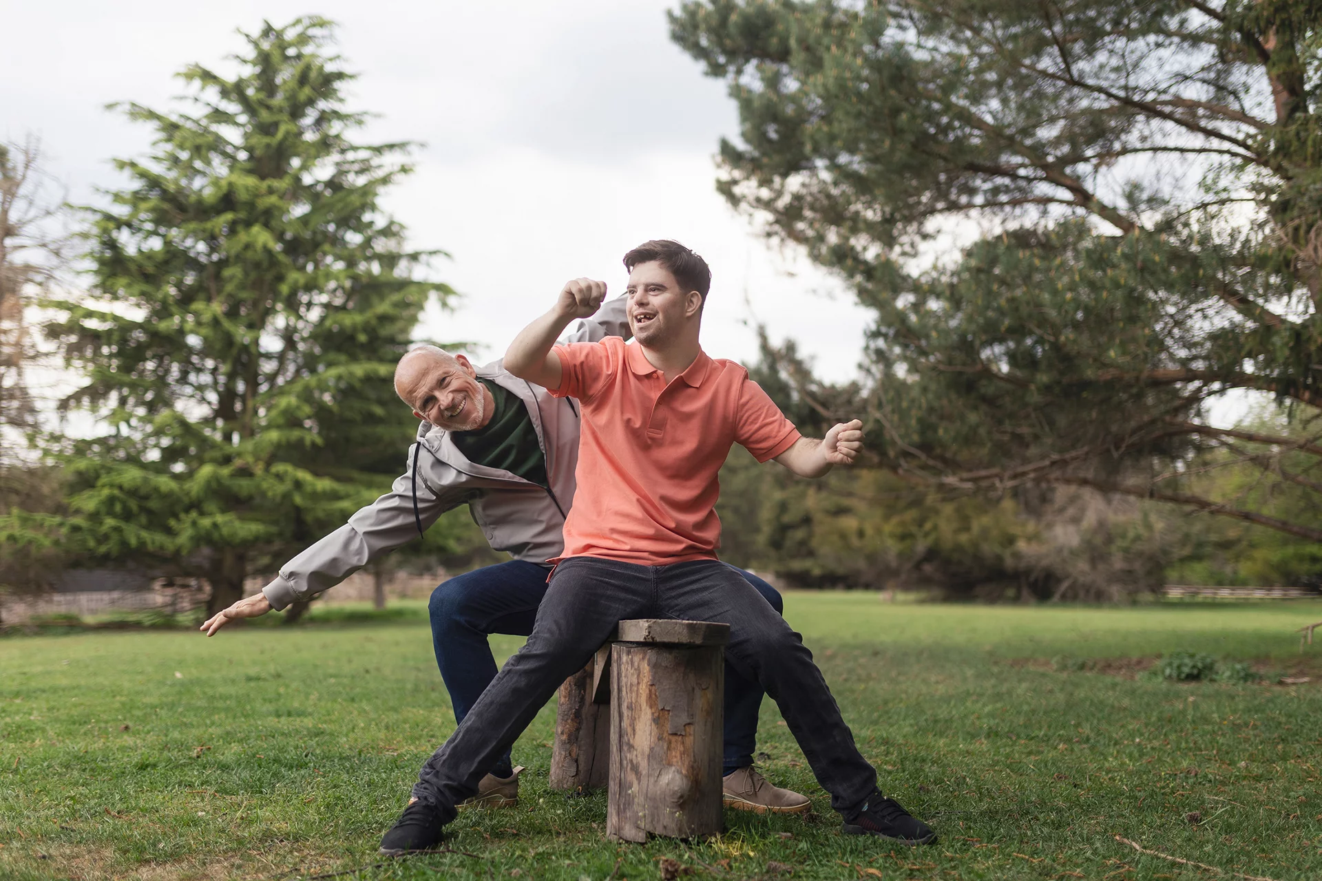 Happy senior father with his young son with Down syndrome sitting and having fun in park.