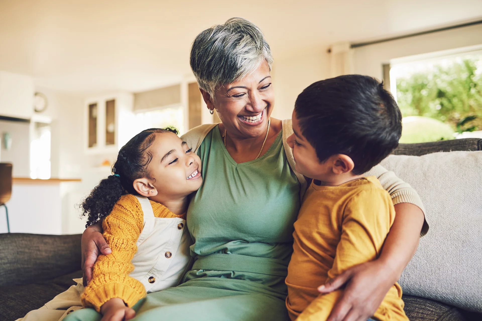 Hug, grandmother or happy kids on a sofa with love enjoying quality bonding time together in family home. Smile, affection or funny senior grandparent with children siblings on house couch laughing.