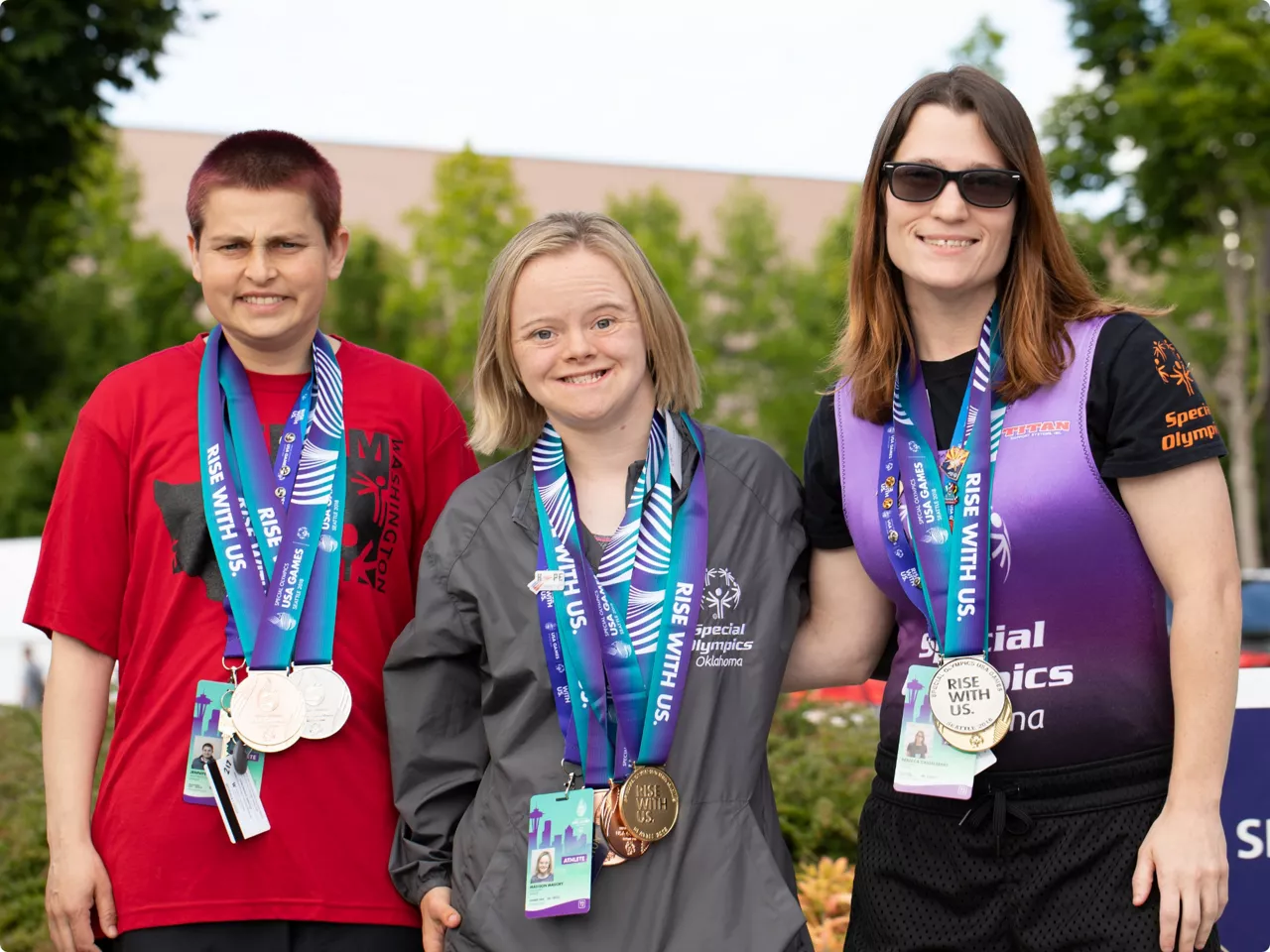 Image of a Special Olympics Event with three individuals smiling
